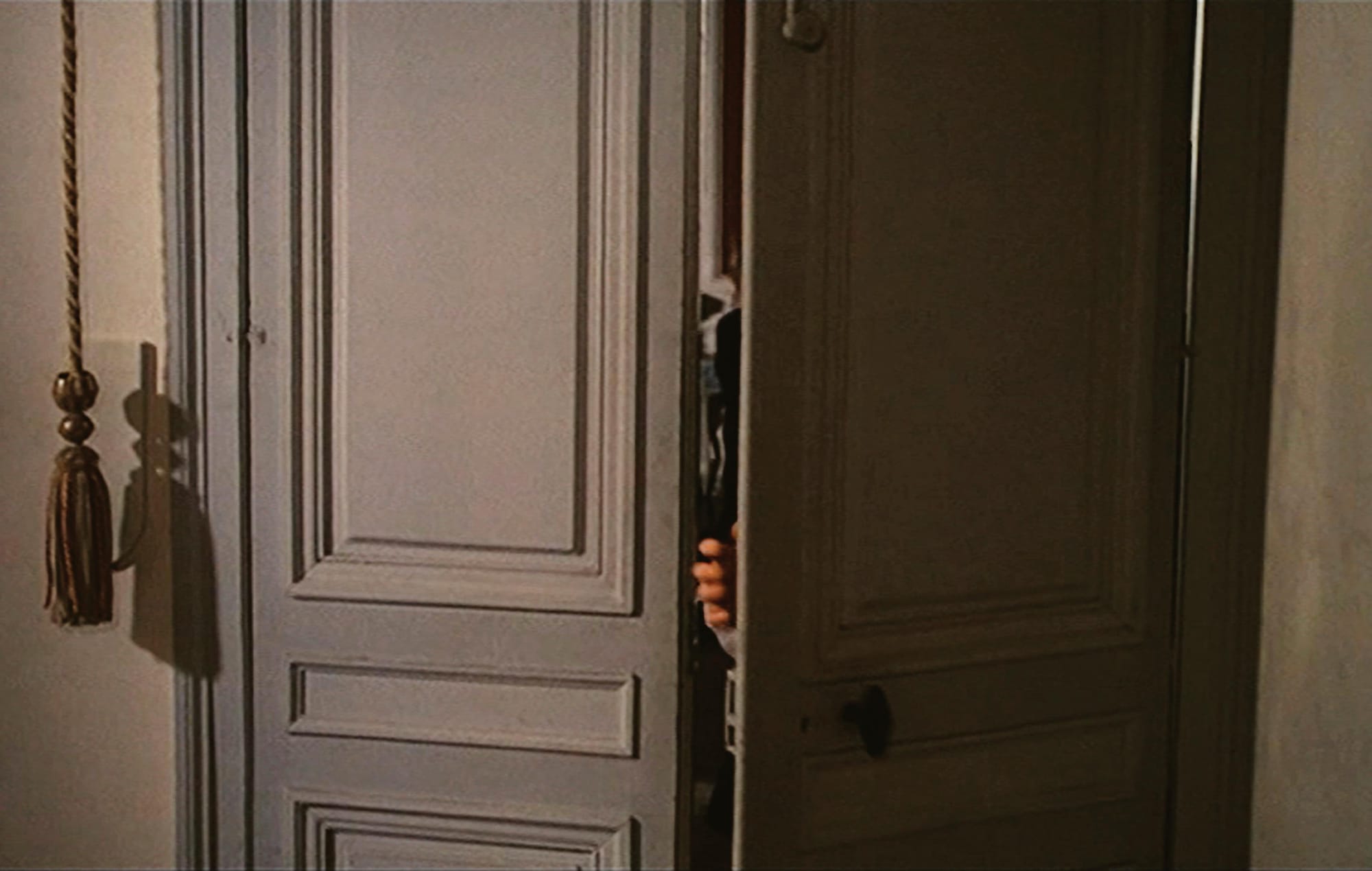 A door opened just slightly, with a hand reaching through the open space.