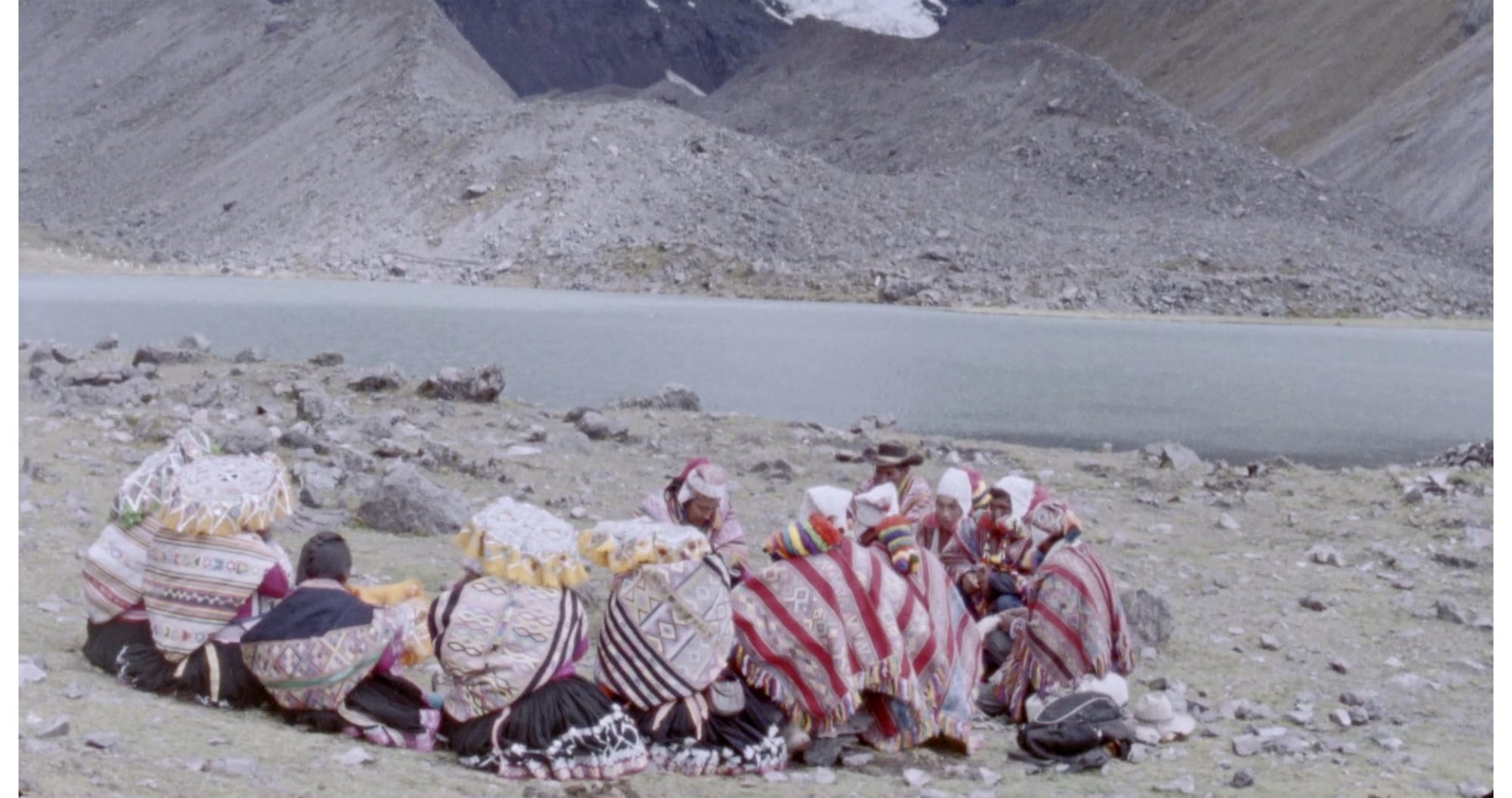 A group of figures in colorful ponchos huddled together in a dusty and rocky landscape.