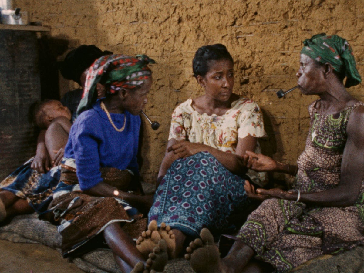 Three African women in colorful dresses sitting on the floor having an important discussion.