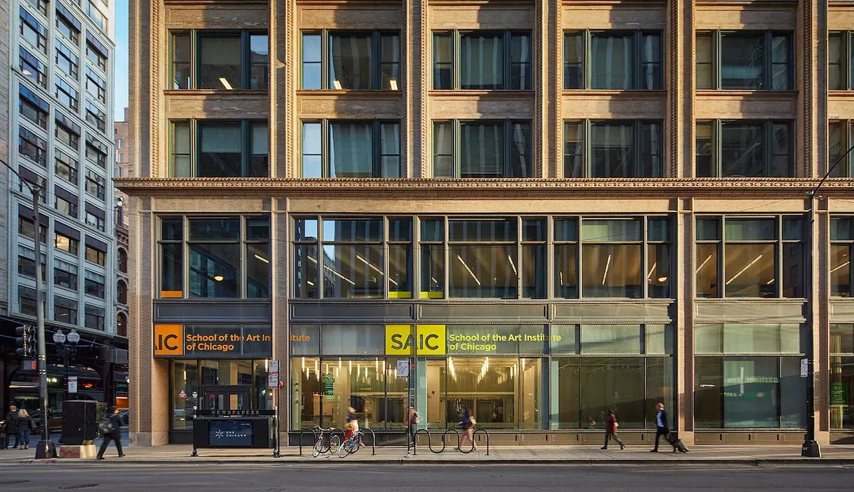 A large building with glass windows on a busy urban street, with the logo for School of the Art Institute of Chicago placed above the main entrance.