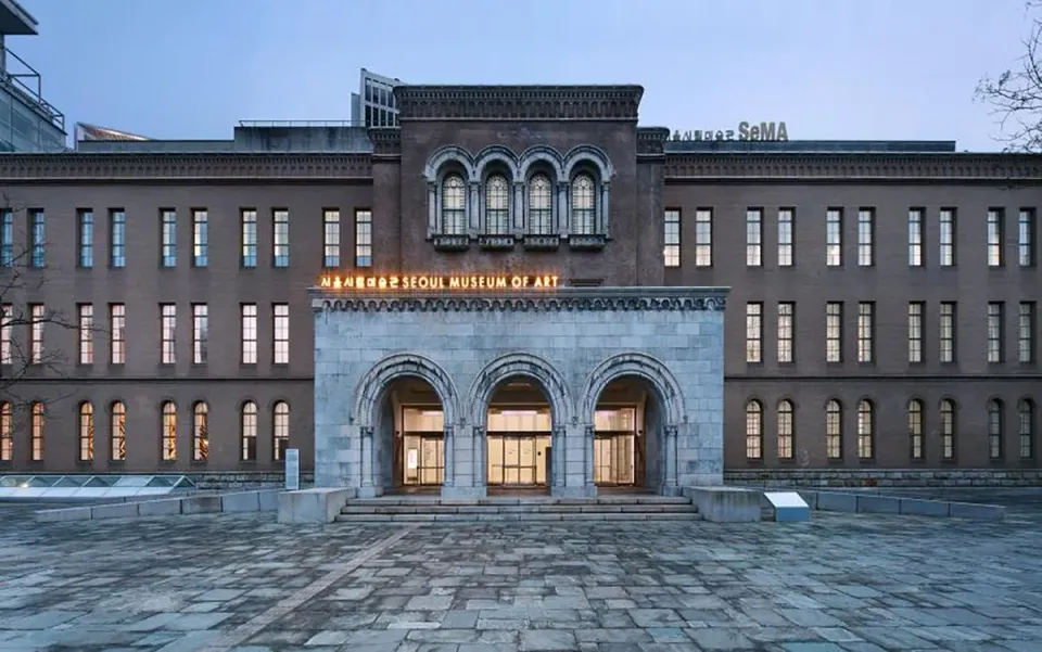 A large art museum with many windows, three arches over the main entrance, and a brown facade.